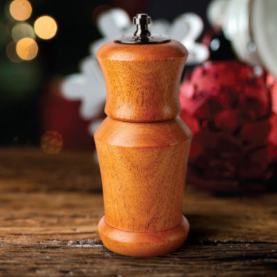 Hand-turned wooden pepper mill with smooth finish on rustic wood surface