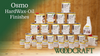Various Osmo Hardwax-Oil finish cans and containers arranged on a wooden surface against a green background.