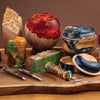 Woodturned bowls, boxes, and pens combining wood with colorful epoxy resin accents on a live edge wood slab.