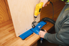 Using a drill with a pocket hole jig to create angled screw holes in plywood on a workbench