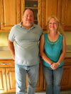 Two people standing in front of oak cabinet doors and drawers in a woodworking shop setting