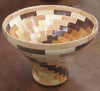 Segmented wooden bowl with alternating light and dark wood pieces in a stepped pattern