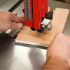 Woodworker using a bandsaw to make a cut to determine what type of bandsaw tune up work he needs to perform.