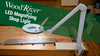 Adjustable WoodRiver LED magnifying lamp clamped to woodworking bench with hardwood board beneath lens