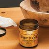 Open jar of Odie's Oil wood finish with wooden bowl and cloth on workbench