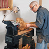 Woodworker shaping a spinning wood blank on a Laguna wood lathe with tool rest and workshop lighting