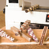 Wooden pen blanks with intricate segmented patterns displayed on a lathe bed in a workshop.