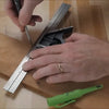 Hand marking precise lines on wood using a combination square and metal ruler in a workshop.