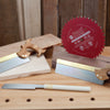 Japanese pull saw, backsaw, and red Freud circular saw blade displayed on woodworking bench