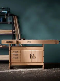 Wooden workbench with drawers against a dark green wall